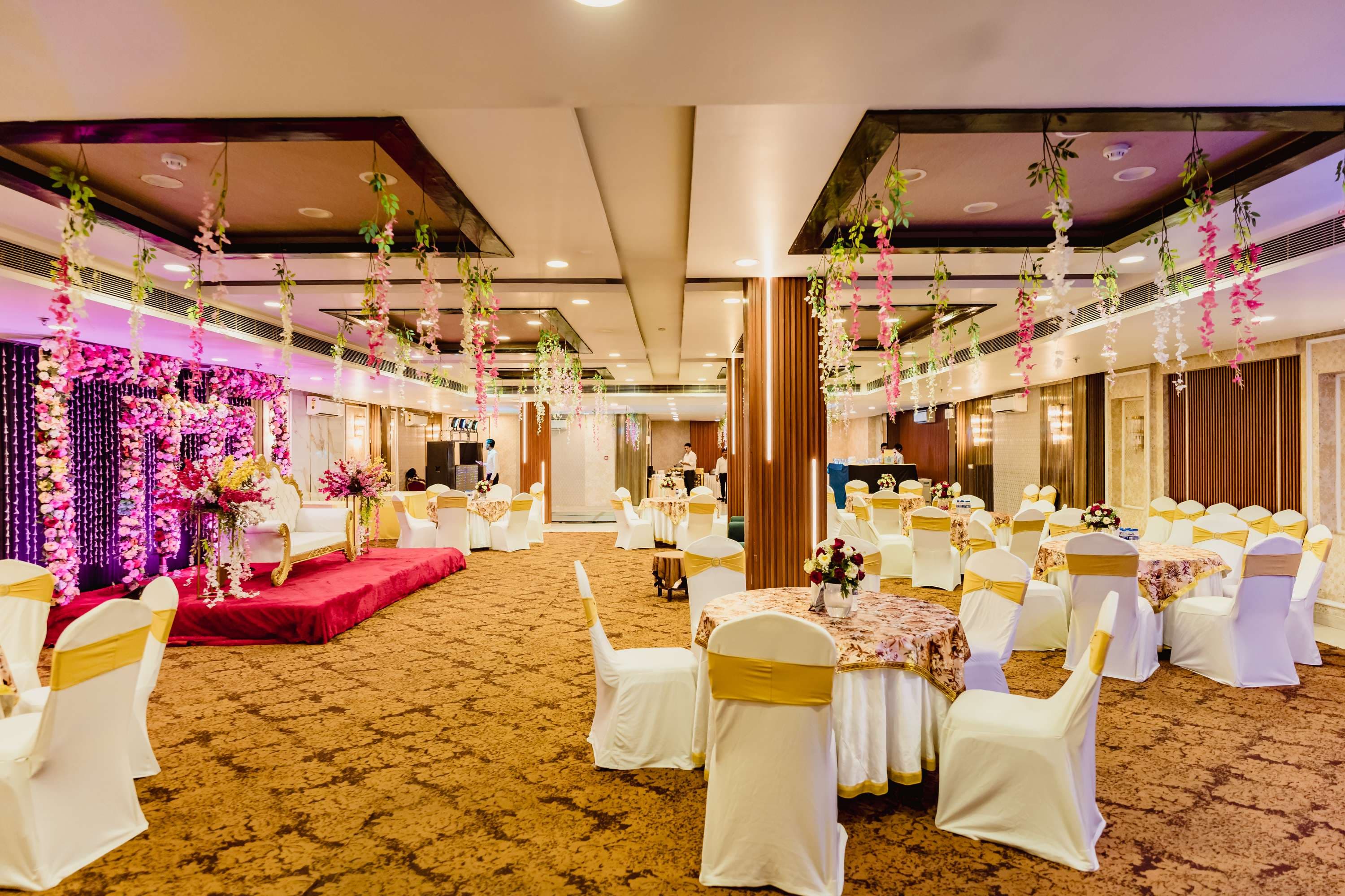 Decorated banquet hall setup in South Delhi with round tables and floral centerpieces